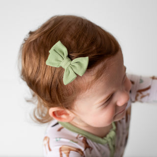 Baby girl wearing sage green clip on bow for babies and toddlers
