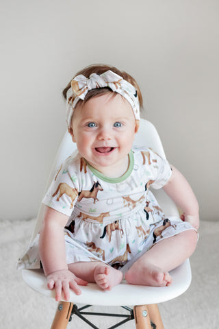 Baby girl wearing headband bow and bamboo bodysuit dress for babies and toddlers in Perfect Ponies print