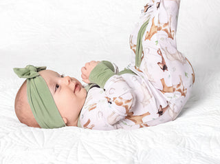Baby girl wearing headband bow and bamboo zipper pajamas for babies and toddlers in Perfect Ponies print