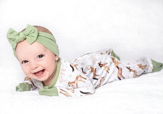 Baby girl wearing headband bow and bamboo zipper pajamas for babies and toddlers in Perfect Ponies print