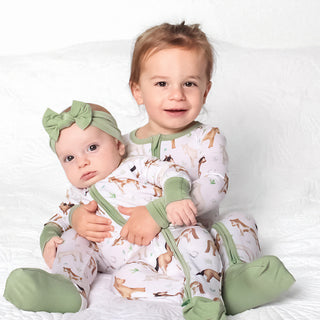 Boy holding baby girl both wearing bamboo zipper pajamas for babies and toddlers in Perfect Ponies print