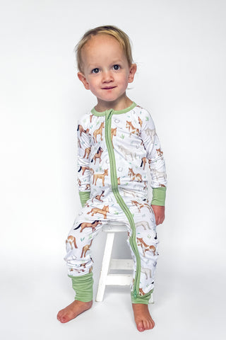 Boy wearing bamboo zipper pajamas for babies and toddlers in Perfect Ponies print