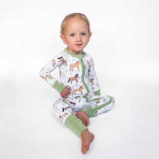 Boy wearing bamboo zipper pajamas for babies and toddlers in Perfect Ponies print