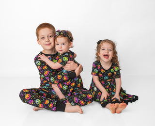 Children wearing bamboo zipper pajamas and dresses for babies, toddlers, and kids in Halloween Pumpkins print