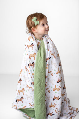 Girl wrapped in bamboo blanket for toddlers and kids in Perfect Ponies print