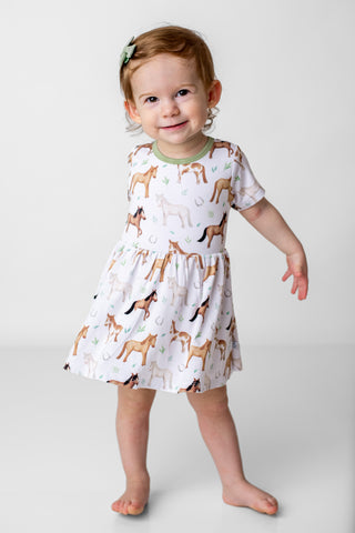 Girl wearing bamboo bodysuit dress for babies and toddlers in Perfect Ponies print