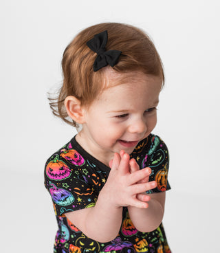 Girl wearing black bamboo clip on bow for babies and toddlers, and kids