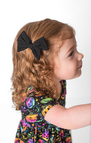 Girl wearing black bamboo clip on bow for toddlers and kids