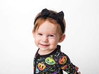 Girl wearing black bamboo headband bow for babies, toddlers, and kids
