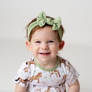 Girl wearing sage green headband bow for toddlers and kids