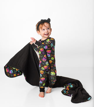 Girl running happily with a bamboo quilted blanket for babies, toddlers, and kids in Halloween Pumpkins print