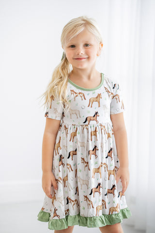 Girl wearing bamboo ruffle dress for toddlers and kids in Perfect Ponies print
