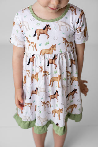 Girl wearing bamboo ruffle dress for toddlers and kids in Perfect Ponies print