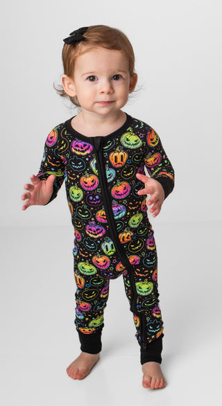 Girl wearing bamboo zipper pajamas for babies and toddlers in Halloween Pumpkins print